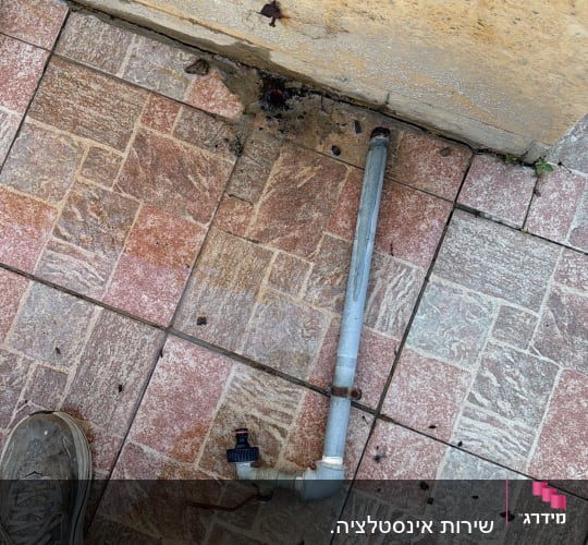 צינור מים על רצפת מרצפות עם נעליים
